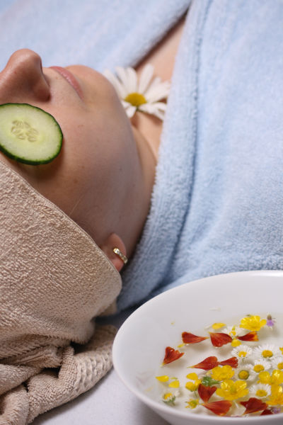 Une femme se détend en peignoir avec des rondelles de concombre sur les yeux